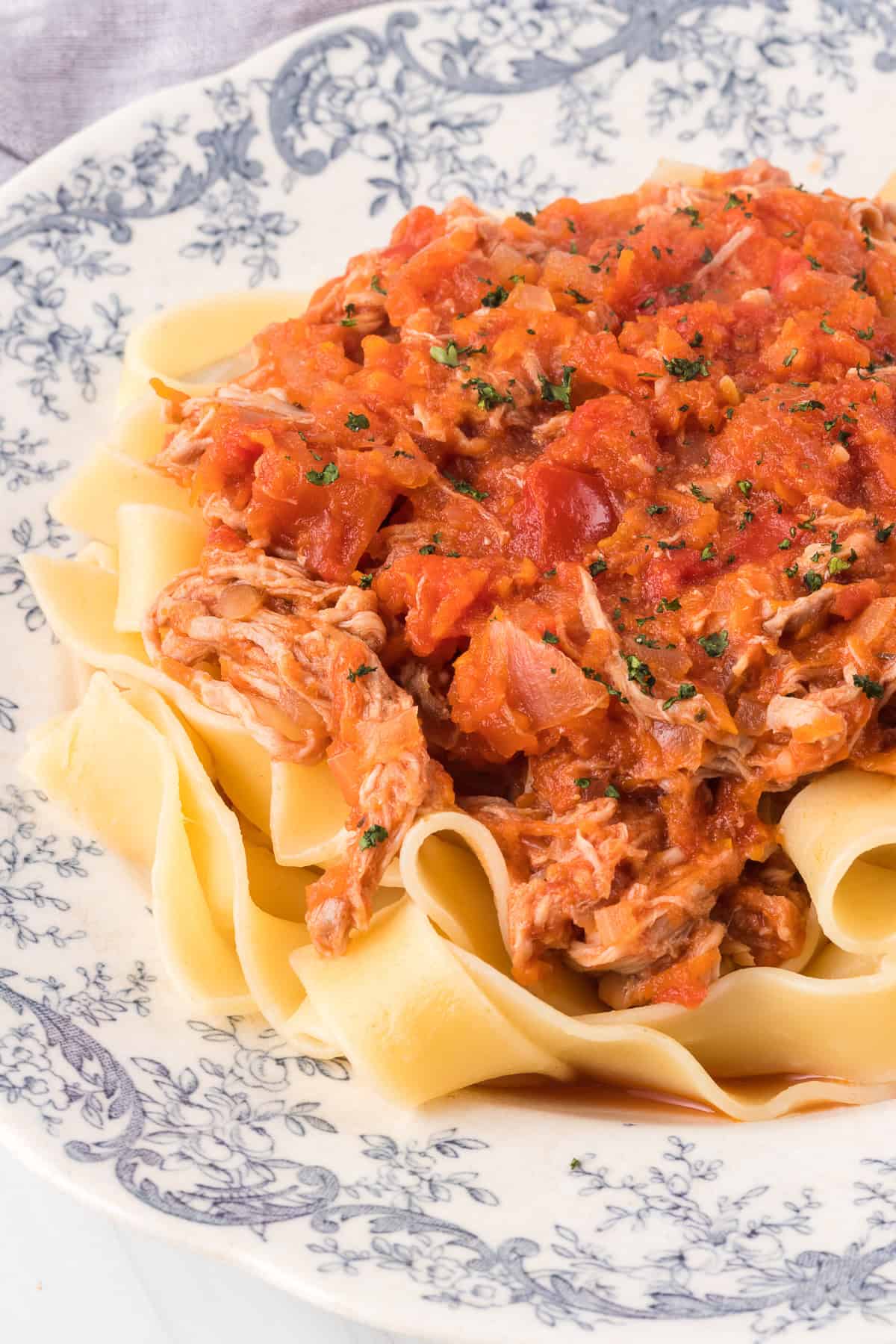 A plate of Pappardelle noodles covered in a red sauce with meat.