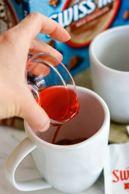 Pouring cherry juice into a cup to make Chocolate Covered Cherry Hot Chocolate.