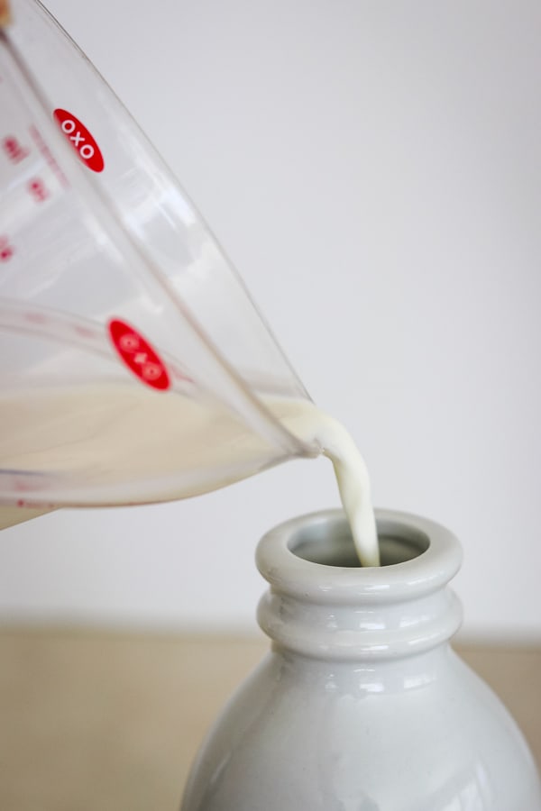 Pouring whole milk into Peppermint White Chocolate Coffee Creamer.