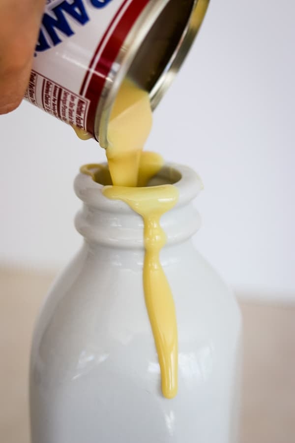 Pouring sweetened condensed milk into Peppermint White Chocolate Coffee Creamer.