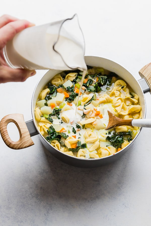 Adding cream to One Pot Bacon and Tortellini Zuppa Toscana.