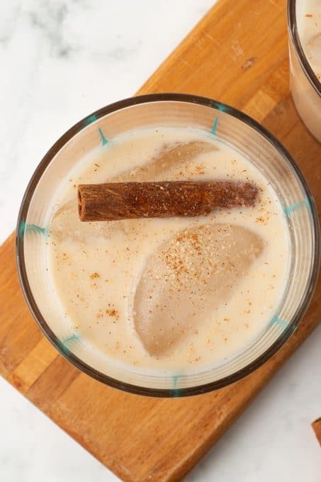 A cinnamon stick and ice cube in a Mexican rice drink.
