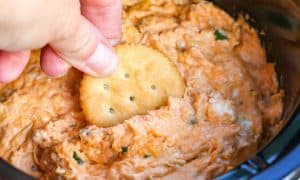 Ritz cracker dipping into the Slow Cooker Buffalo Chicken Dip.
