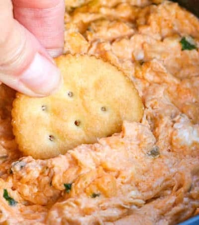 Ritz cracker dipping into the Slow Cooker Buffalo Chicken Dip.