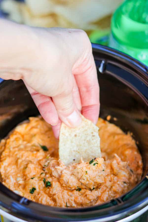 A tortilla chip dipping into the Slow Cooker Buffalo Chicken Dip.