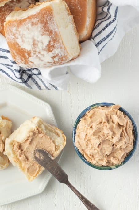 Spreading butter with honey and cinnamon on a dinner roll.