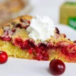A Une tranche de recette de tarte aux canneberges facile garnie de crème fouettée et de canneberges.
