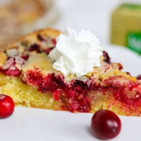 A A slice of Easy Cranberry Pie Recipe topped with whipped cream and cranberries.