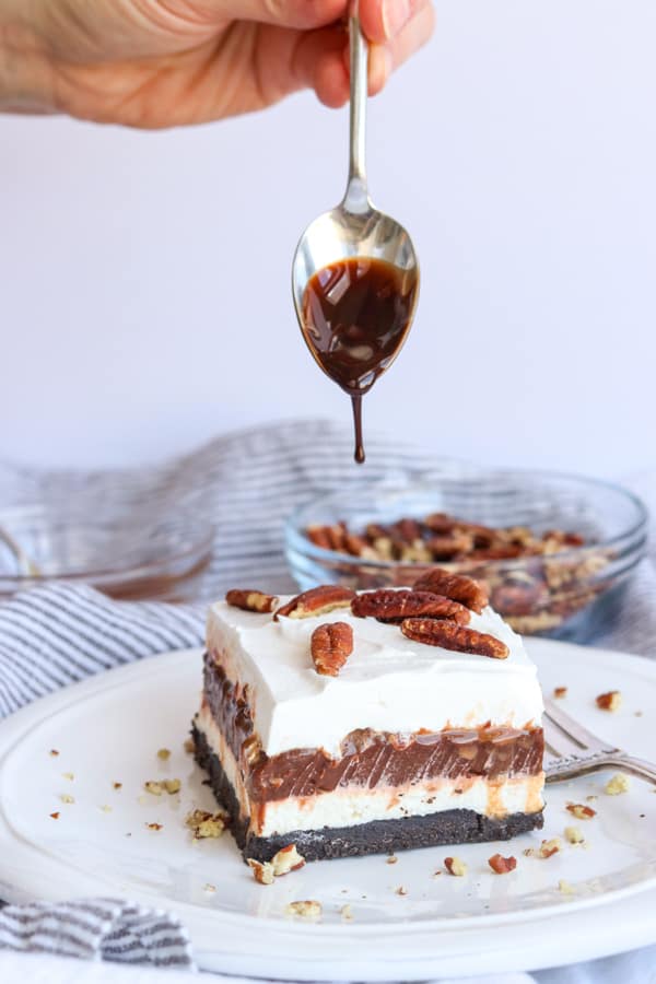Drizzling chocolate on top of a No Bake Turtle Dream Bar.