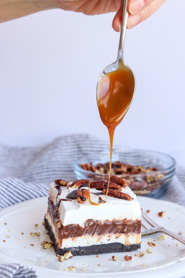 Drizzling caramel on top of a No Bake Turtle Dream Bar.