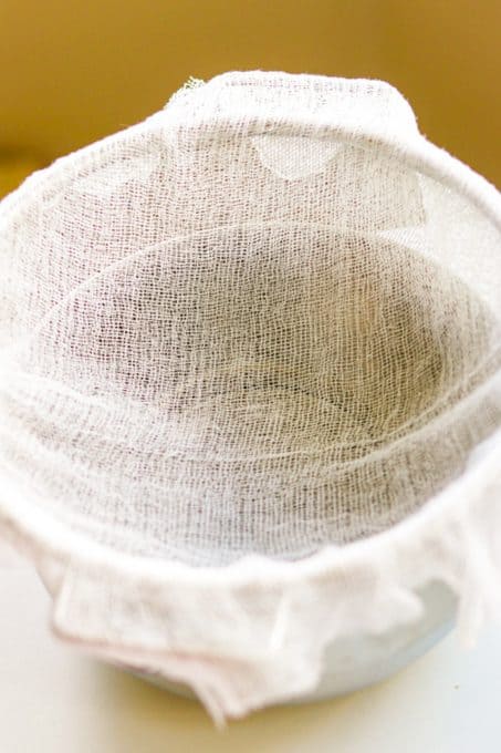 Lining a bowl with cheesecloth to drain the cottage cheese for blnitzes.