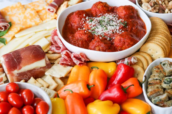 Meatballs, small peppers, tomatoes on a meat and cheese board / charcuterie. 