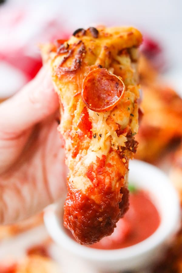 A slice of Pepperoni Bread Twist dipped in marinara.