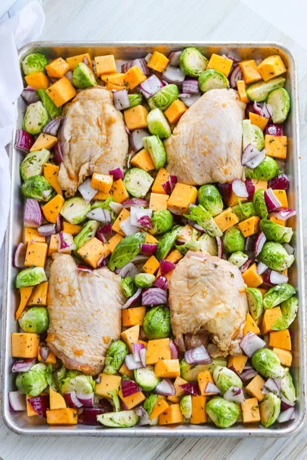 Chicken thighs and vegetables on a baking sheet.
