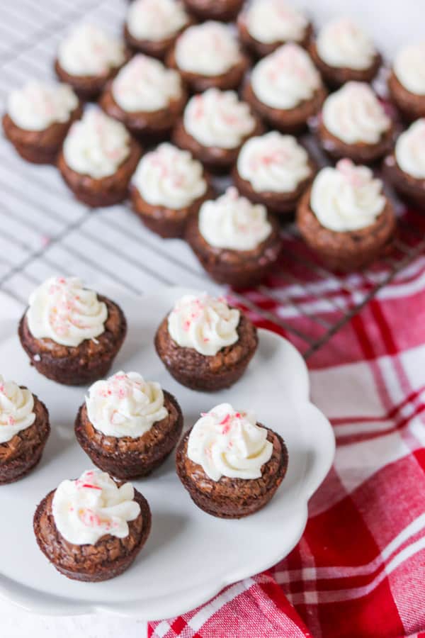 Frosted peppermint brownie bites with crushed candy canes on top.