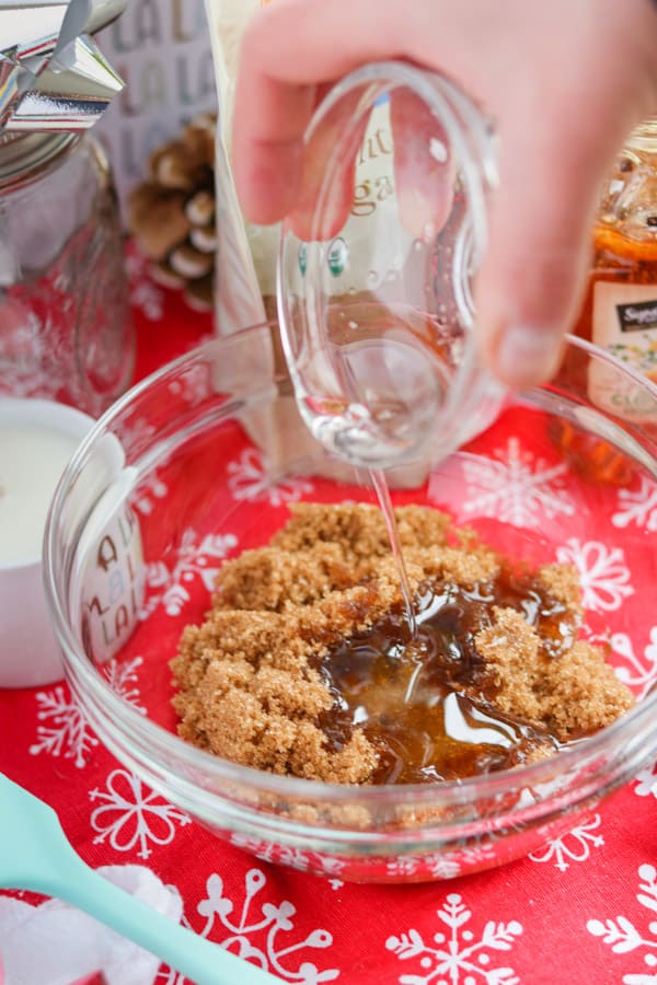 Pouring coconut oil into brown sugar to make a scrub.