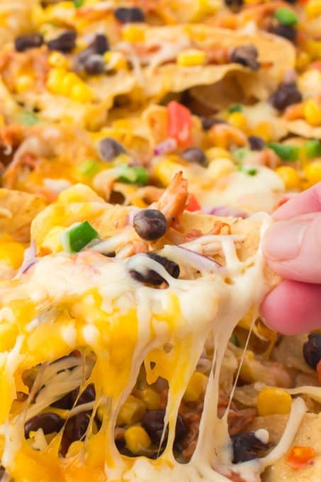 Pulling a nacho full of cheese and toppings.