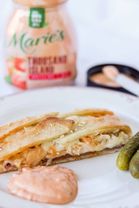 A plate with pickles, Marie's Thousand Island Dressing and a Reuben Braid slice.