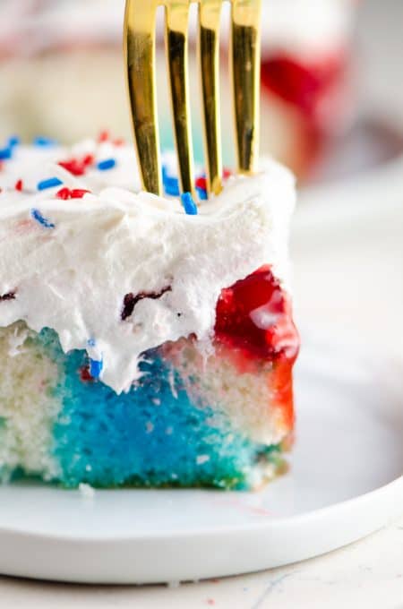 Fork digging into a slice of red, white, and blue cake.
