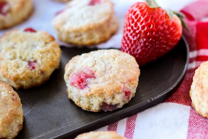 A scone with strawberries topped with raw sugar.