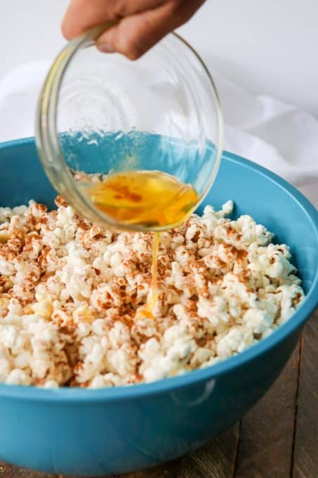 Pouring ghee over popcorn with cinnamon sugar.