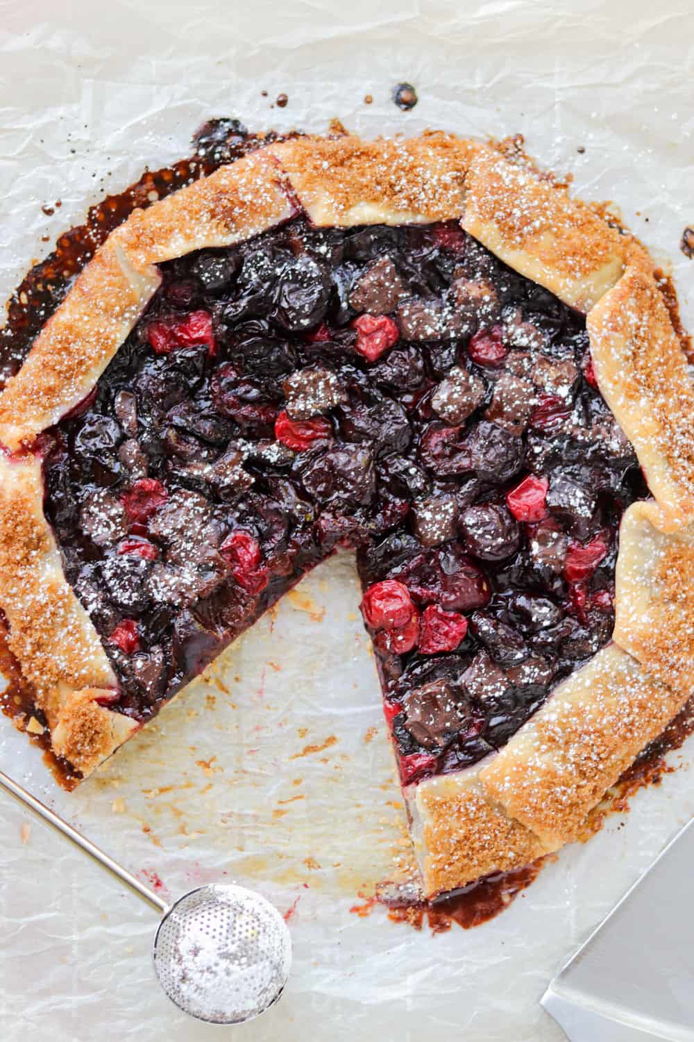 A piece removed from a galette with cherries and dark chocolate.