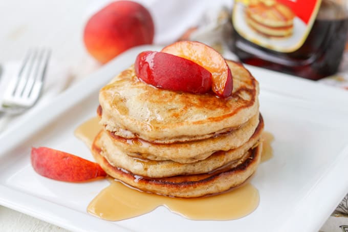 Cinnamon Pancakes topped with peaches and maple syrup.