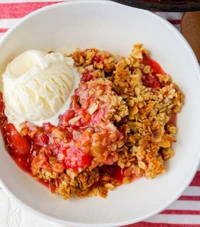 A bowl of Skillet Strawberry Rhubarb Crisp with a scoop of ice cream.