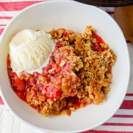 A bowl of Skillet Strawberry Rhubarb Crisp with a scoop of ice cream.