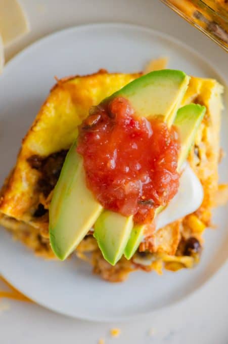 Avocado and salsa top a slice of Mexican chorizo breakfast casserole.