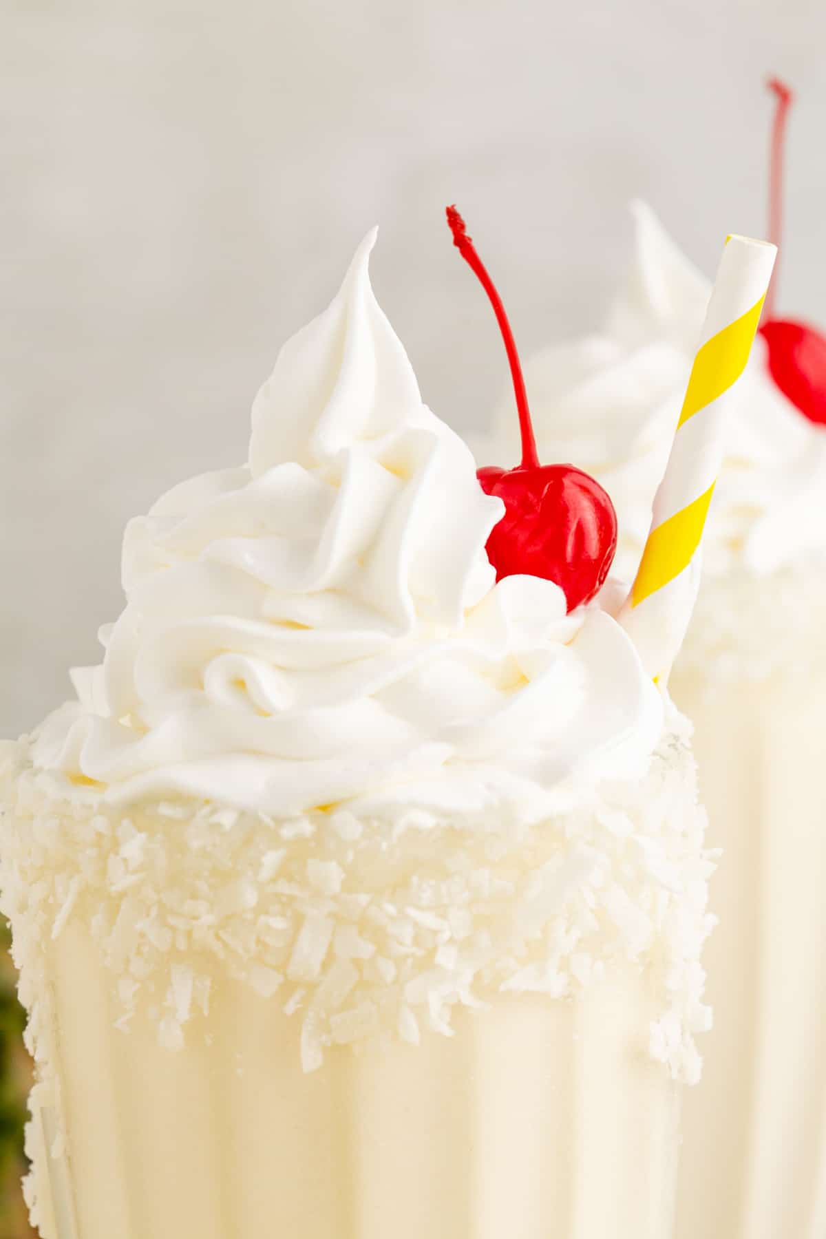 A cherry and whipped cream on top of a milkshake with rum and coconut.