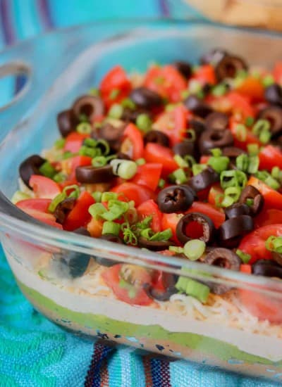 Layers of beans, guacamole, sour cream, tomatoes, olives, green onions and cheese.