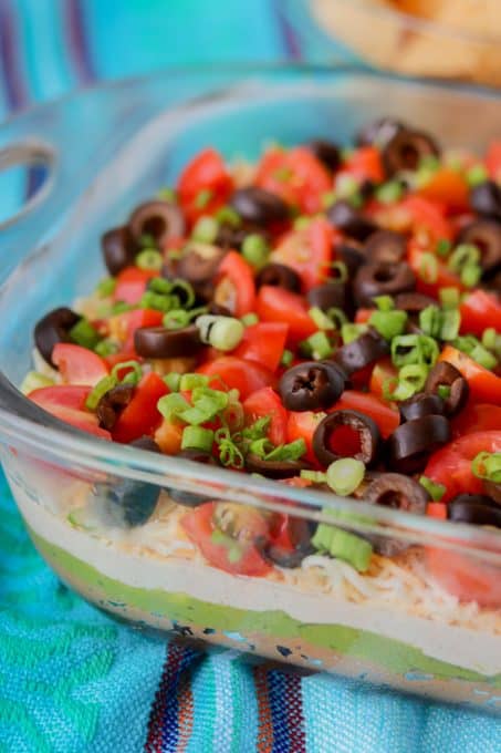 Layers of beans, guacamole, sour cream, tomatoes, olives, green onions and cheese.