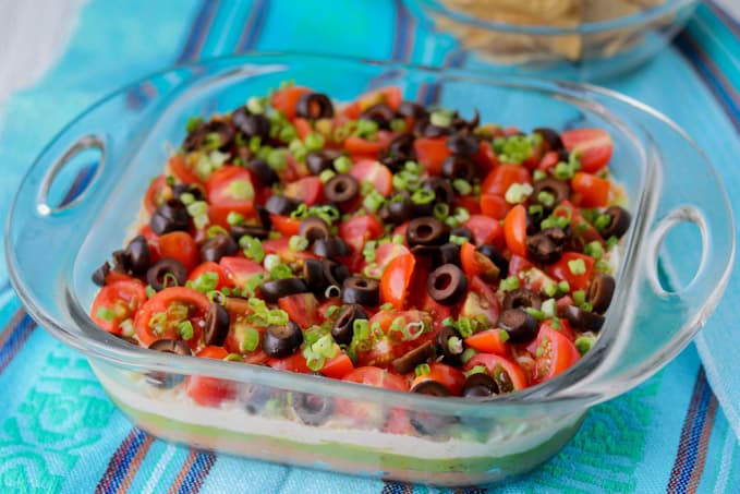 Layers of beans, guacamole, sour cream, tomatoes, olives, green onions and cheese.