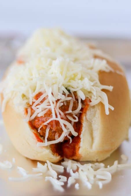 A meatball sandwich covered with cheese.