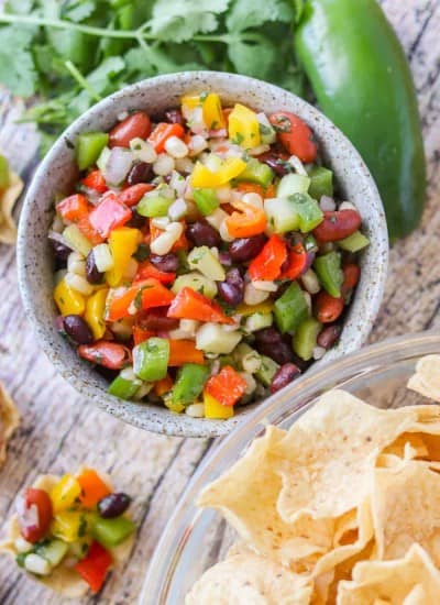 A bowl of corn, diced bell peppers, red onion, beans in a zesty marinade.