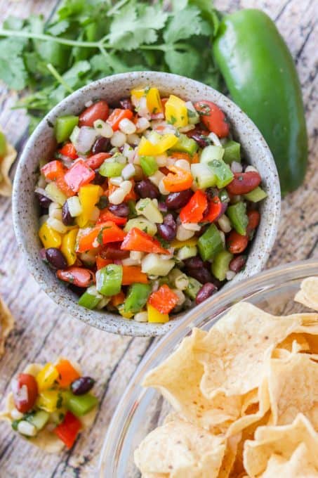 A bowl of corn, diced bell peppers, red onion, beans in a zesty marinade.