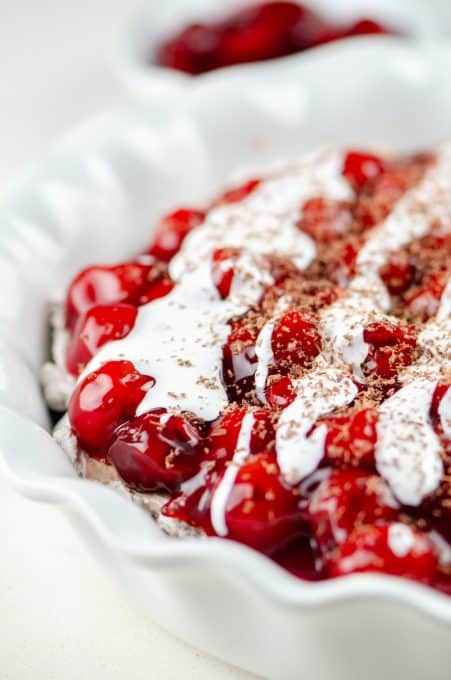 Cherry topping on chocolate cheesecake drizzled with marshmallow topping.