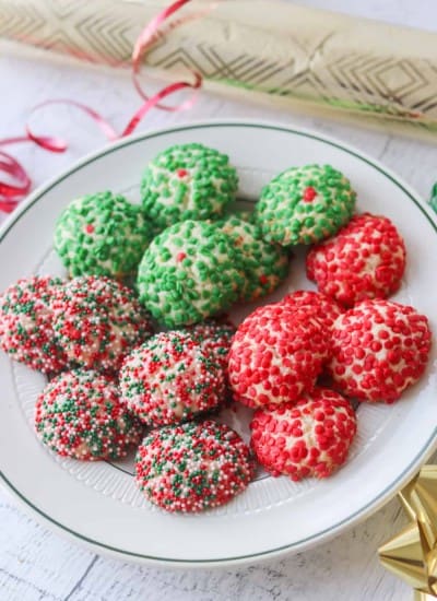 A plate full of cream cheese cookies covered in sprinkles.