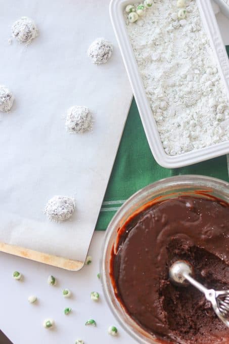 Rolling dough for Crinkle Cookies in powdered sugar and crushed wasabi peas.