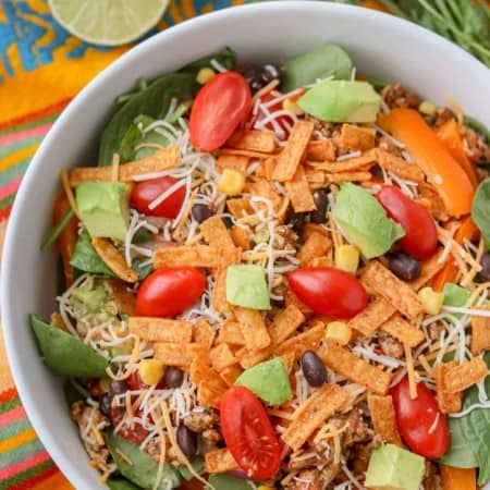 A bowl of salad with taco seasoned chicken, spinach, black beans, corn, and more.