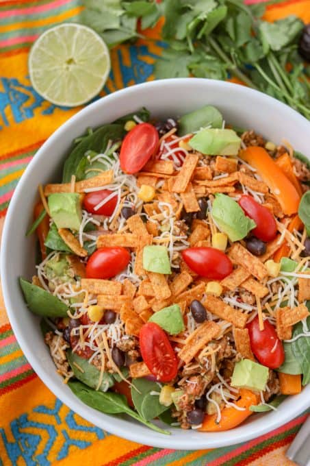 A bowl of salad with taco seasoned chicken, spinach, black beans, corn, and more.