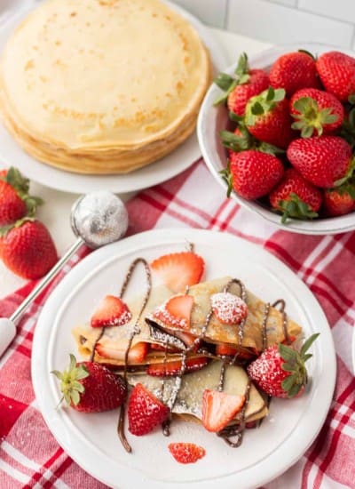 A plate full of crepes filled with strawberries and Nutella.