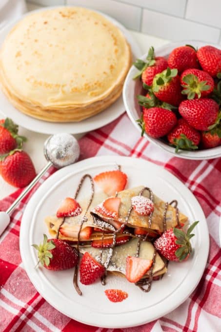 A plate full of crepes filled with strawberries and Nutella.