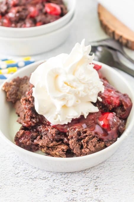 Whipped Cream on top of a cake with cherry pie filling.