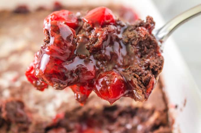 A spoonful of a chocolate dump cake with cherries.