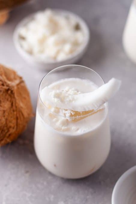 A coconut drink with a piece of coconut.