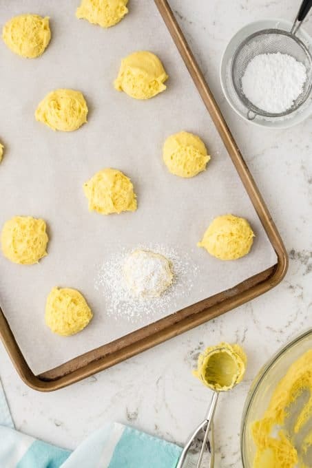 Putting powdered sugar on cake mix cookies.