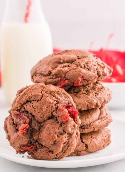 A stack of chocolate cake cookies with maraschino cherries inside.