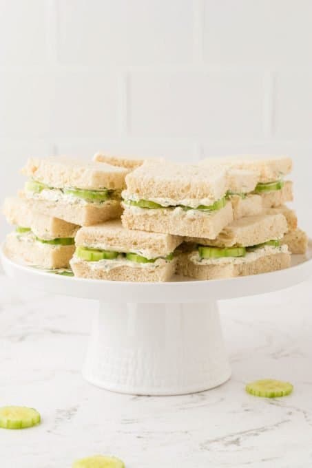 A plate of sandwiches of cucumber and seasoned cream cheese.